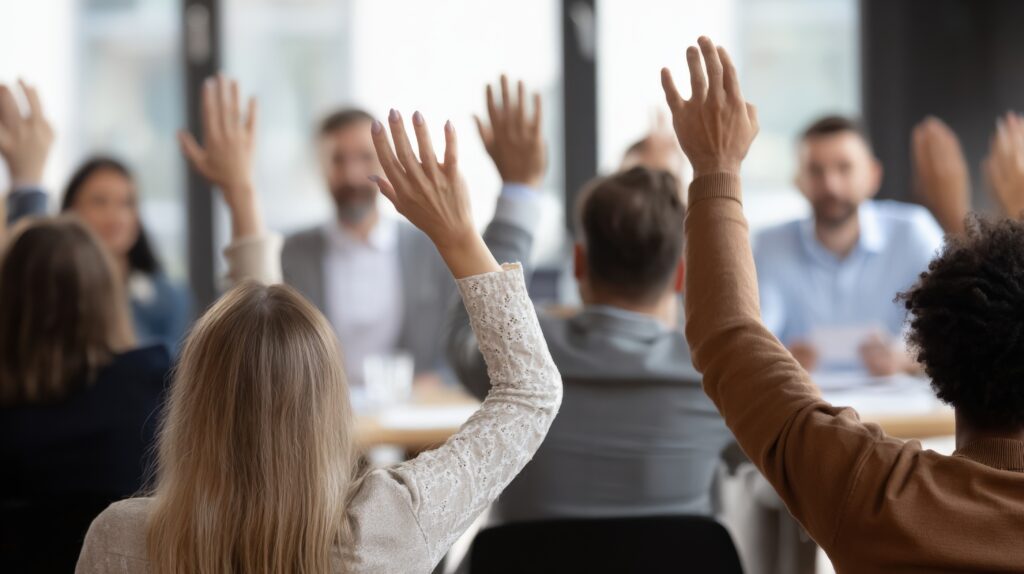 Diverse Group Raising Hands in Meeting: Active Participation and Engagement in Business Setting