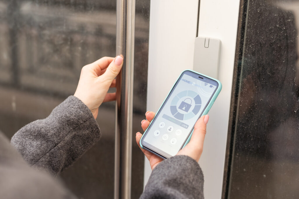 Woman locking smartlock on the entrance door using a smart phone. Concept of using smart electronic locks with keyless access
