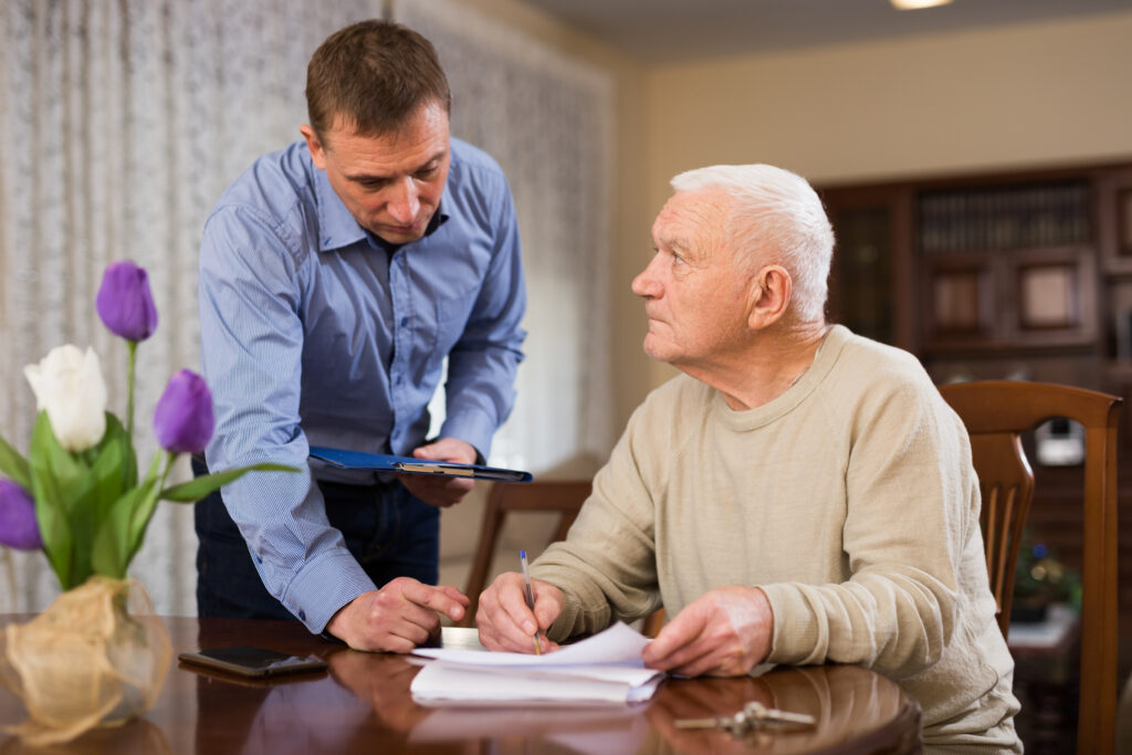 Troubled senior man discussing documents with his adult son while sitting at home table
