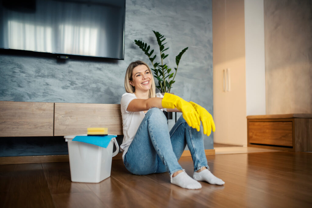 A tidy woman relaxes on the floor after cleaning the house.